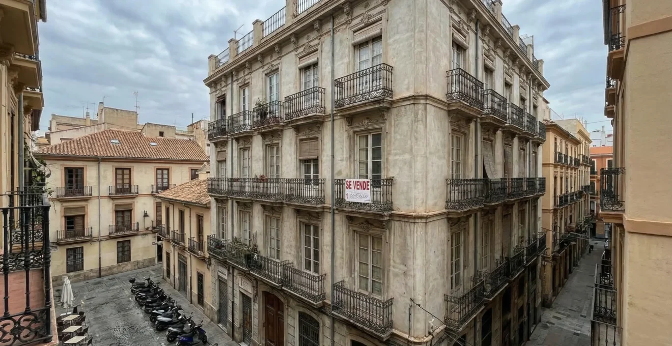 Edificio residencial español con cartel de se vende en balcón
